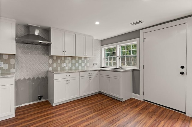 kitchen with dark hardwood / wood-style flooring, white cabinetry, sink, and wall chimney exhaust hood