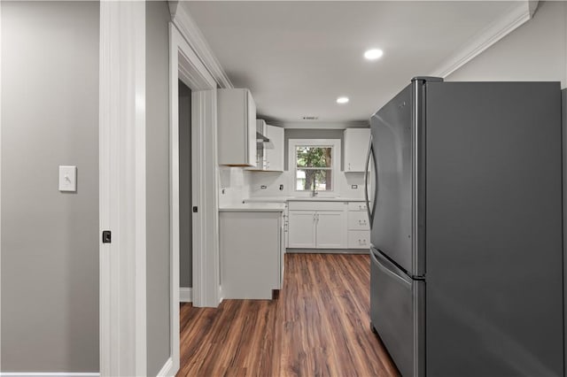 kitchen featuring white cabinets, crown molding, dark hardwood / wood-style floors, tasteful backsplash, and stainless steel refrigerator