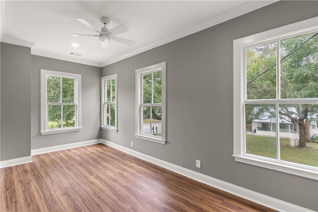 spare room featuring ceiling fan, plenty of natural light, wood-type flooring, and ornamental molding