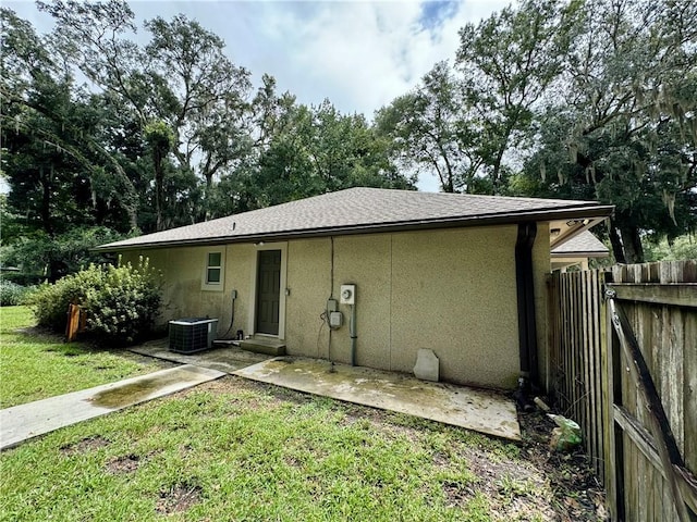 back of property featuring central air condition unit, fence, a yard, stucco siding, and a patio area