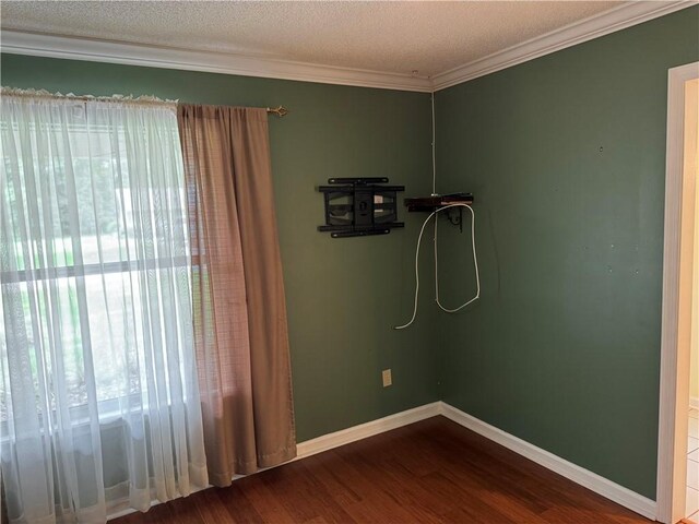 empty room featuring crown molding, a textured ceiling, baseboards, and wood finished floors