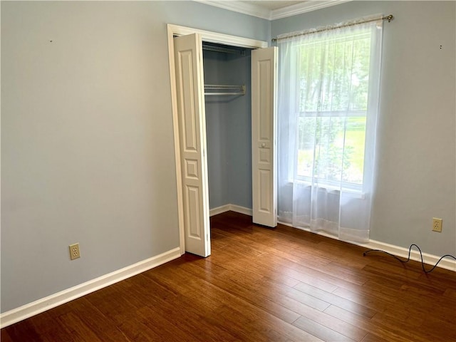 unfurnished bedroom featuring a closet, dark wood finished floors, and baseboards