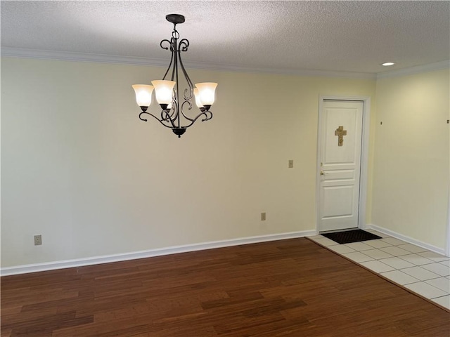 unfurnished dining area with a textured ceiling, ornamental molding, and wood finished floors