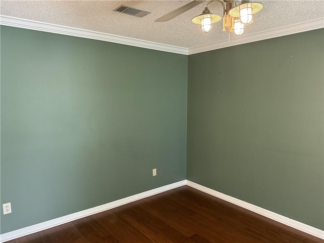 empty room with visible vents, dark wood-type flooring, ornamental molding, a textured ceiling, and baseboards