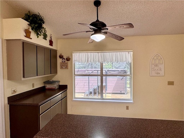 interior space featuring a ceiling fan, dark countertops, a textured ceiling, and gray cabinetry