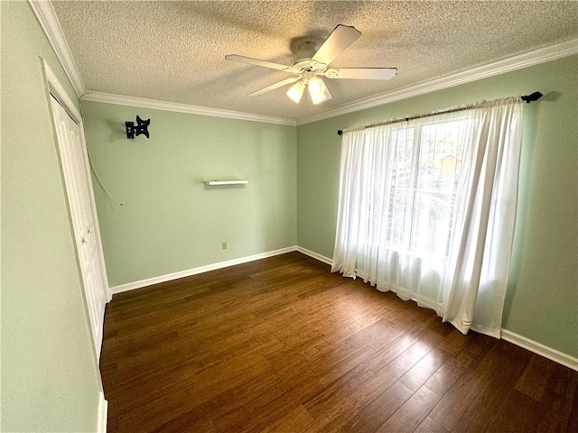 empty room featuring baseboards, ceiling fan, ornamental molding, and dark wood-type flooring