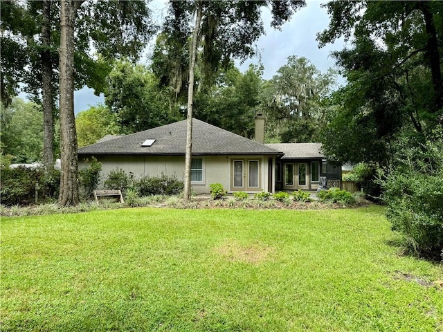 back of house with french doors, roof with shingles, a lawn, stucco siding, and a chimney