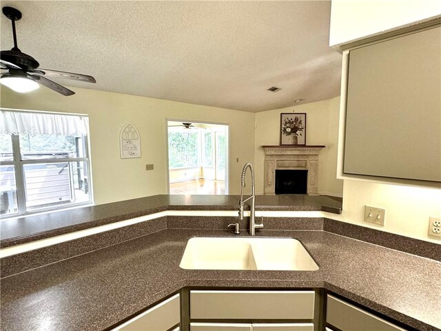 kitchen with open floor plan, a fireplace, a sink, and a textured ceiling