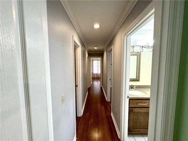 hall with light wood-style floors, baseboards, ornamental molding, and a sink