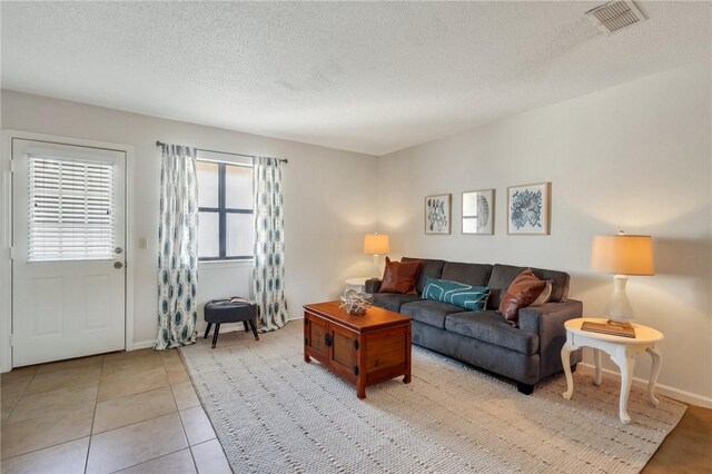 living room featuring visible vents, baseboards, a textured ceiling, and light tile patterned flooring