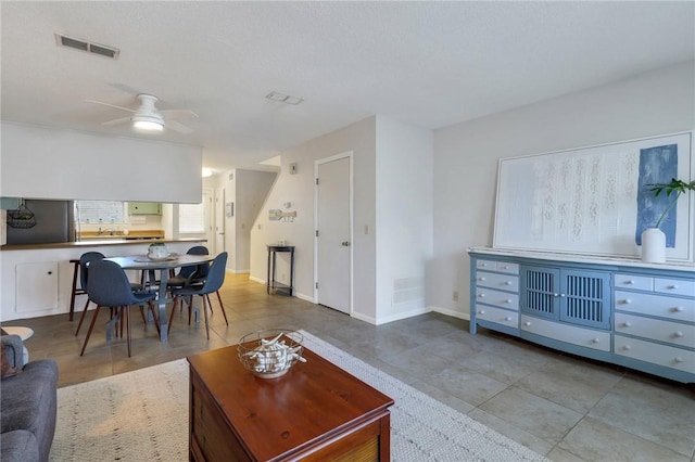 tiled living room with a ceiling fan, baseboards, and visible vents