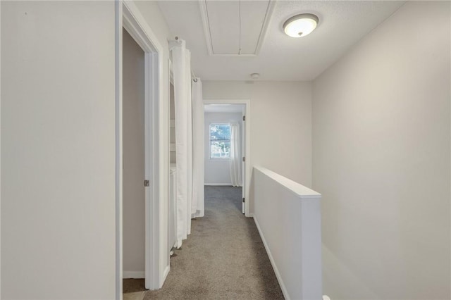 hallway featuring an upstairs landing, baseboards, attic access, and carpet