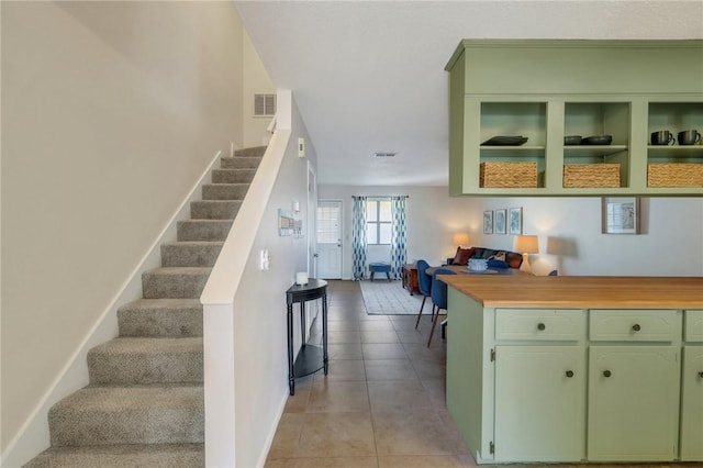 stairway featuring tile patterned floors, visible vents, and baseboards