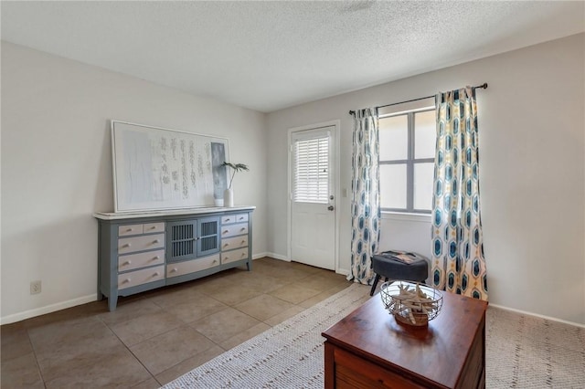 entryway with tile patterned floors, a textured ceiling, and baseboards