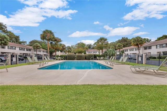 community pool with a residential view, a lawn, and fence