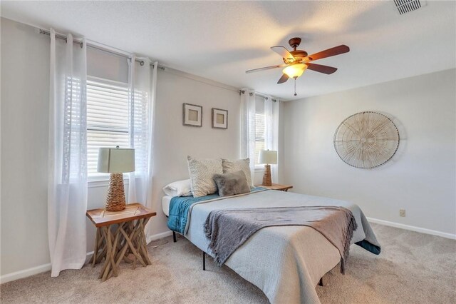 bedroom with visible vents, baseboards, and light carpet