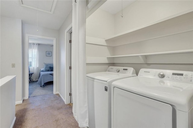 clothes washing area with baseboards, attic access, light carpet, laundry area, and separate washer and dryer