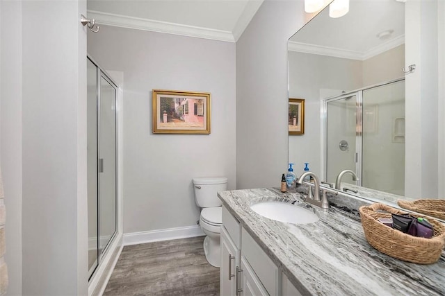 bathroom with toilet, a shower with shower door, crown molding, vanity, and hardwood / wood-style floors