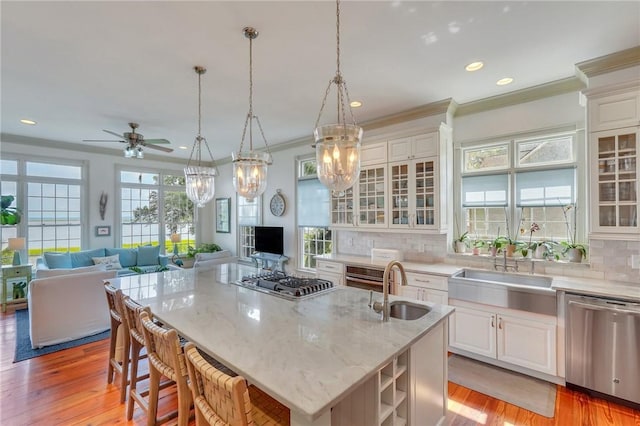 kitchen featuring a breakfast bar, appliances with stainless steel finishes, hanging light fixtures, an island with sink, and white cabinets