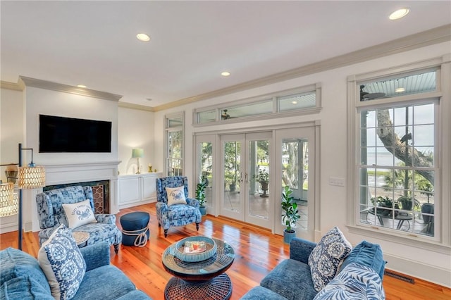 living room featuring crown molding, hardwood / wood-style floors, a fireplace, and french doors