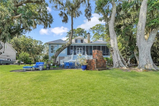 back of property with a sunroom, an outdoor hangout area, and a lawn