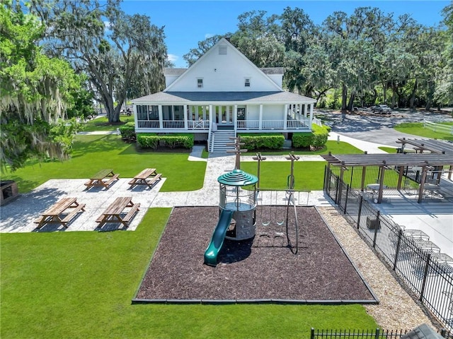 rear view of house with a playground, a sunroom, a yard, and a patio area