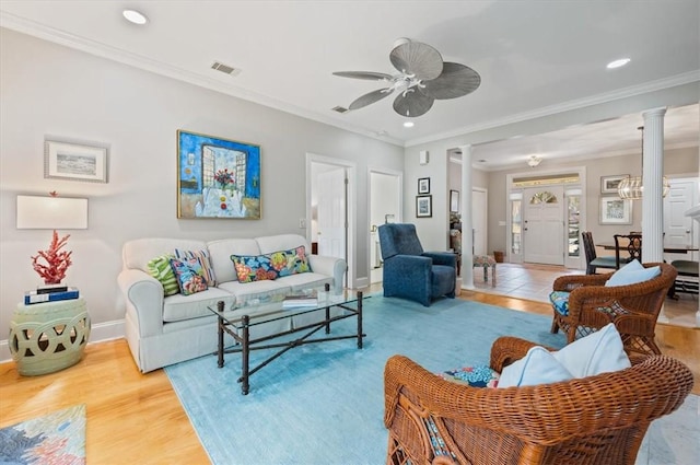 living room with hardwood / wood-style floors, decorative columns, ceiling fan, and crown molding