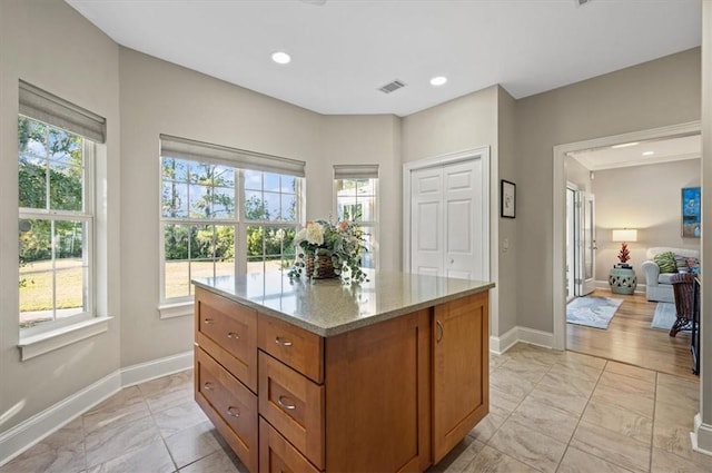 23 W Lake Dr, Saint Simons Island, GA 31522 - kitchen with light marble finish flooring, baseboards, brown cabinets, light stone counters, and recessed lighting