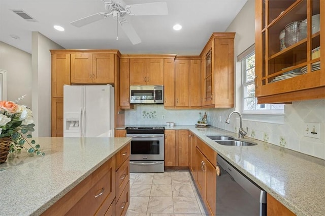 23 W Lake Dr, Saint Simons Island, GA 31522 - kitchen with appliances with stainless steel finishes, a sink, light stone countertops, glass insert cabinets, and a ceiling fan