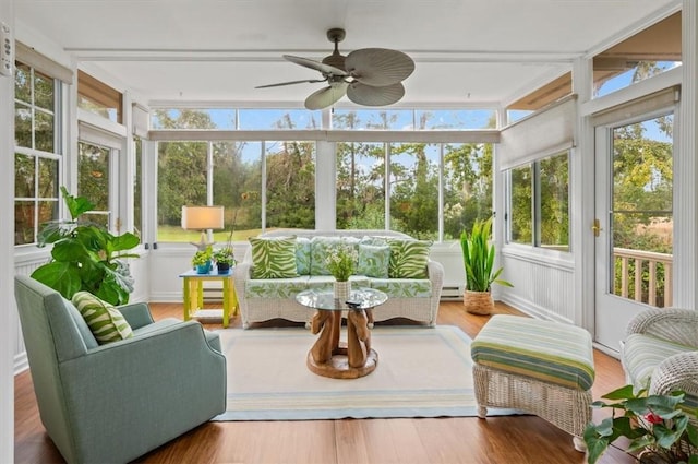 sunroom with ceiling fan and a baseboard heating unit