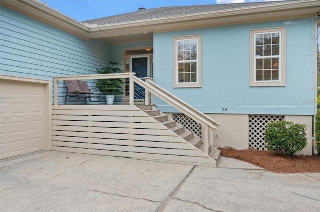 23 W Lake Dr, Saint Simons Island, GA 31522 - doorway to property with stucco siding, an attached garage, roof with shingles, and driveway