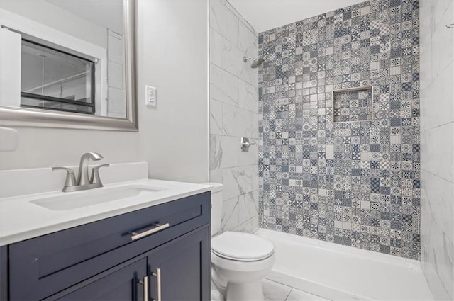 bathroom featuring a tile shower, vanity, toilet, and tile patterned floors