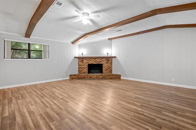 unfurnished living room with hardwood / wood-style floors, wood walls, a brick fireplace, ceiling fan, and a textured ceiling