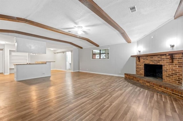 unfurnished living room featuring vaulted ceiling with beams, a fireplace, wood-type flooring, and a textured ceiling