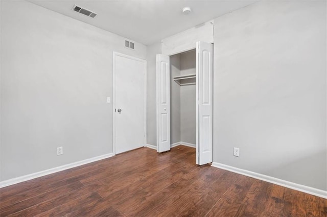 unfurnished bedroom with a closet and dark hardwood / wood-style floors