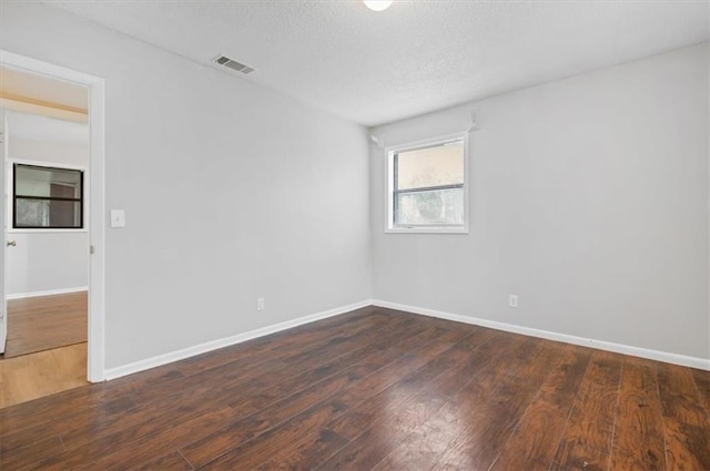 empty room with a textured ceiling and dark hardwood / wood-style flooring