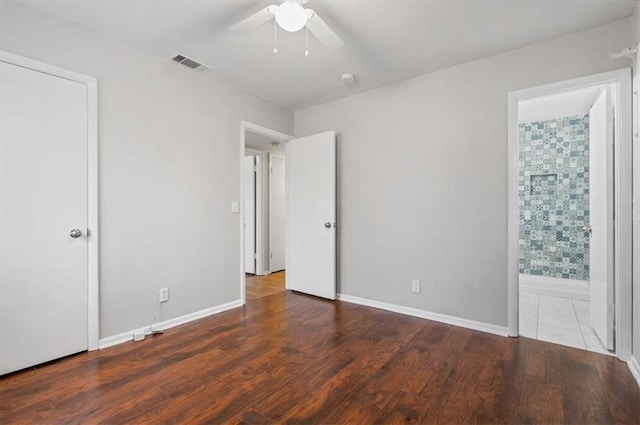 unfurnished bedroom featuring dark hardwood / wood-style flooring, ensuite bath, and ceiling fan