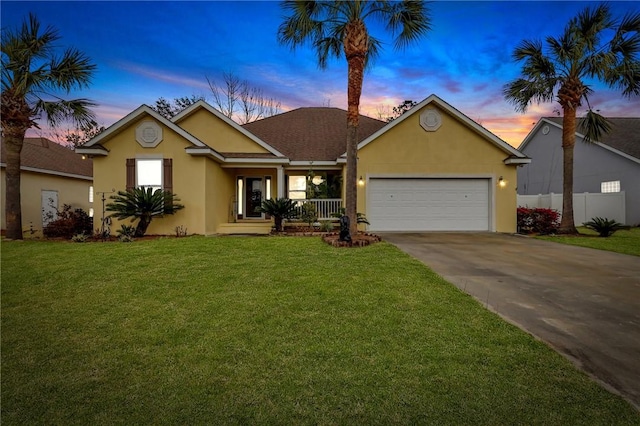 ranch-style home featuring concrete driveway, an attached garage, fence, a front lawn, and stucco siding