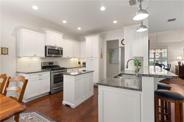 1045 Sinclair Pointe Pt, Saint Simons Island, GA 31522 - kitchen featuring stainless steel appliances, white cabinets, backsplash, a kitchen bar, and recessed lighting