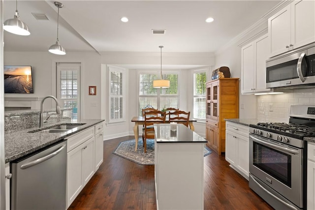 1045 Sinclair Pointe Pt, Saint Simons Island, GA 31522 - kitchen featuring appliances with stainless steel finishes, a kitchen island, dark wood finished floors, backsplash, and white cabinetry