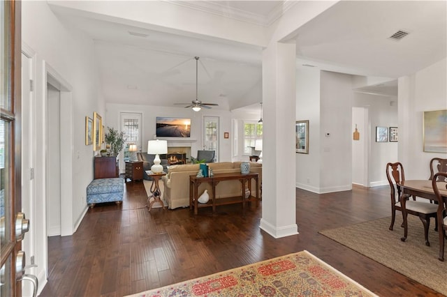 1045 Sinclair Pointe Pt, Saint Simons Island, GA 31522 - living room with lofted ceiling, dark wood-type flooring, a ceiling fan, a lit fireplace, and ornamental molding