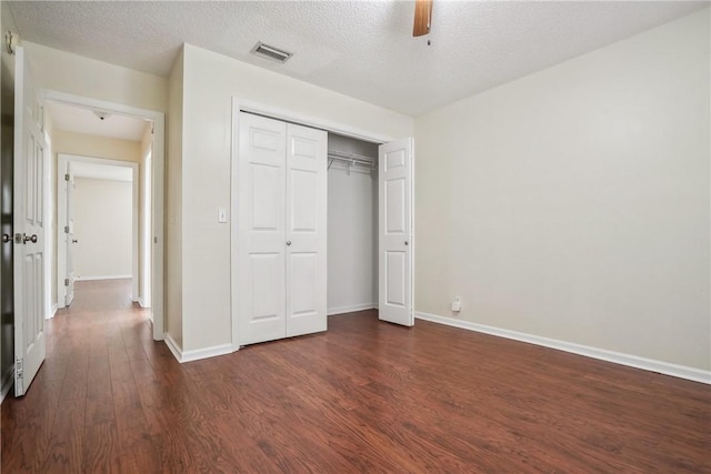 unfurnished bedroom with a closet, a textured ceiling, dark hardwood / wood-style floors, and ceiling fan