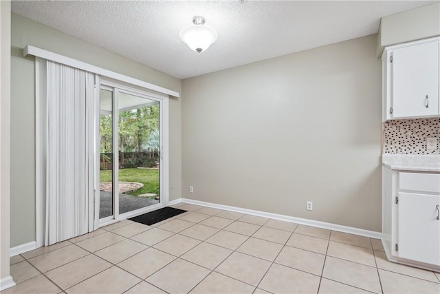 unfurnished dining area with light tile patterned floors and a textured ceiling