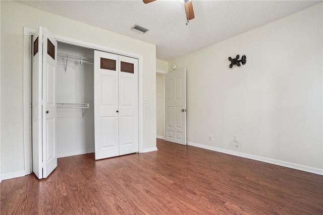 unfurnished bedroom featuring ceiling fan, dark hardwood / wood-style flooring, a textured ceiling, and a closet