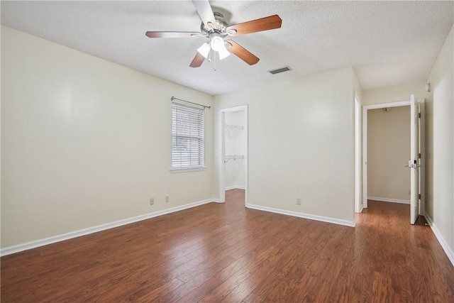 unfurnished room with a textured ceiling, ceiling fan, and dark hardwood / wood-style floors