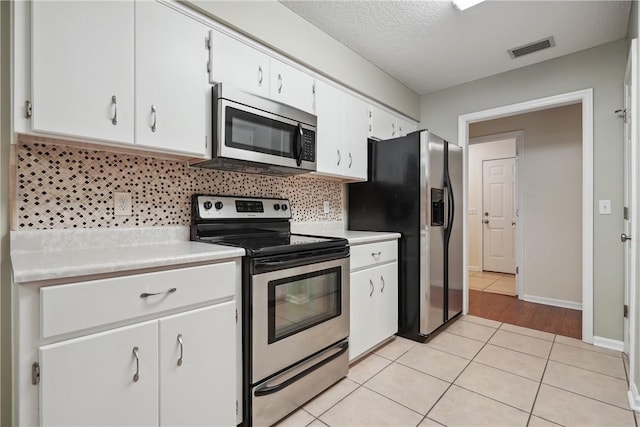 kitchen with decorative backsplash, a textured ceiling, stainless steel appliances, light tile patterned floors, and white cabinetry