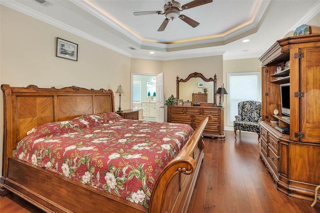 bedroom featuring dark wood-type flooring, ensuite bathroom, crown molding, ceiling fan, and a tray ceiling