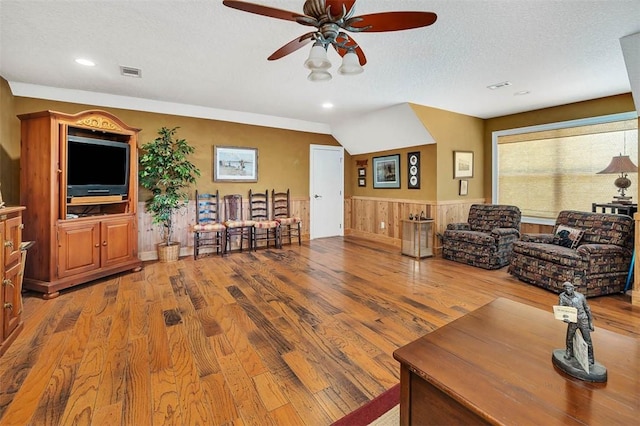 living room featuring a textured ceiling, hardwood / wood-style flooring, and ceiling fan