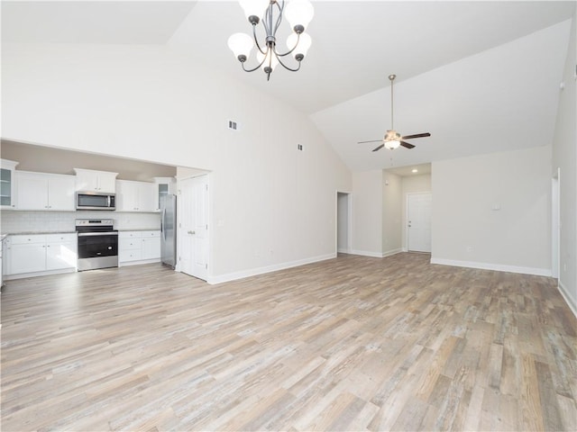 unfurnished living room with ceiling fan with notable chandelier, light wood-type flooring, and high vaulted ceiling