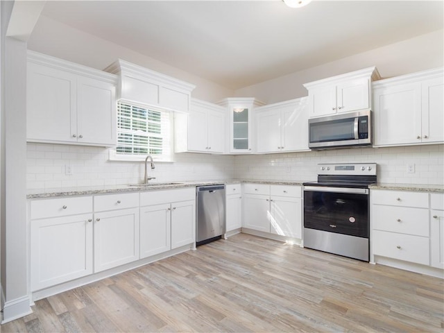 kitchen featuring sink, white cabinets, stainless steel appliances, and light wood-type flooring